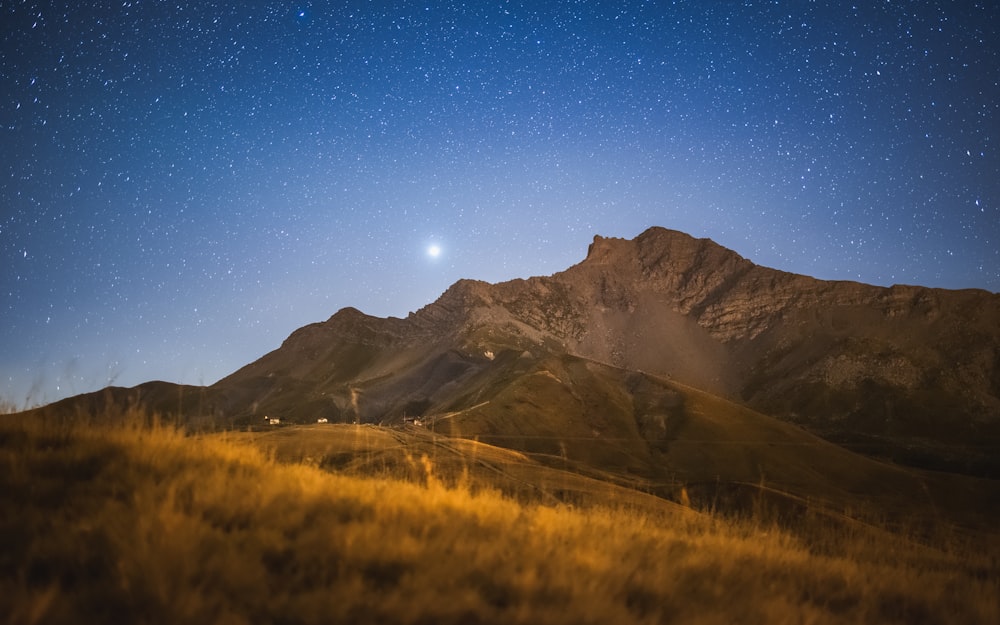 the night sky with stars above a mountain range