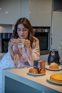 Happy woman enjoying a morning ritual with a cup of herbal tea in a cozy kitchen.
