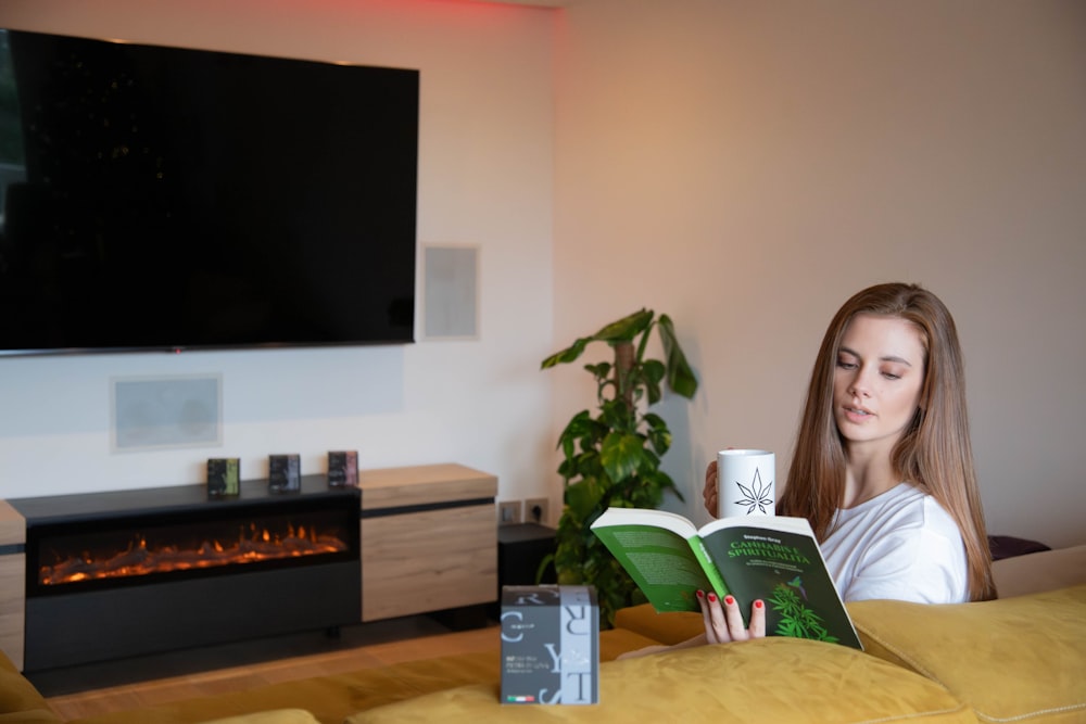 a woman sitting on a couch reading a book