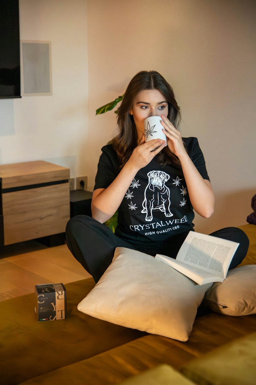 a woman sitting on a bed drinking from a mug