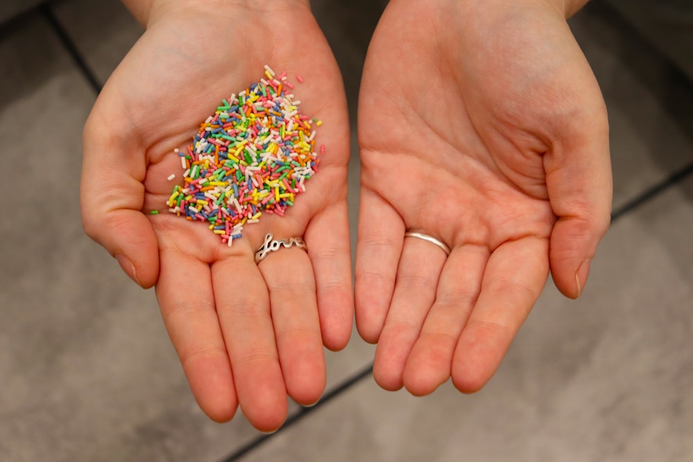 a person holding a handful of sprinkles in their hands