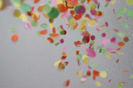 Close-up of colorful confetti pieces being cut by rotary dies in a factory setting.