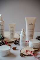A collection of skincare products from the brand Plandae displayed on wooden rounds, accompanied by festive elements like pinecones, acorns, and candy canes. The arrangement creates a natural and holiday-themed aesthetic.