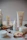 A collection of skincare products from the brand Plandae displayed on wooden rounds, accompanied by festive elements like pinecones, acorns, and candy canes. The arrangement creates a natural and holiday-themed aesthetic.