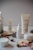 A collection of skincare products from the brand Plandae displayed on wooden rounds, accompanied by festive elements like pinecones, acorns, and candy canes. The arrangement creates a natural and holiday-themed aesthetic.