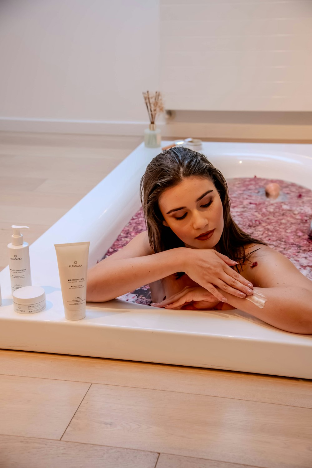 a woman laying in a bathtub with a lot of cream