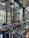 A modern, stylish interior space featuring glass walls and wooden accents. The area is decorated with festive garlands adorned with ornaments and lights. There are plants visible outside the glass, adding a touch of greenery. Warm and cozy lighting enhances the inviting atmosphere.