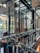 A modern, stylish interior space featuring glass walls and wooden accents. The area is decorated with festive garlands adorned with ornaments and lights. There are plants visible outside the glass, adding a touch of greenery. Warm and cozy lighting enhances the inviting atmosphere.