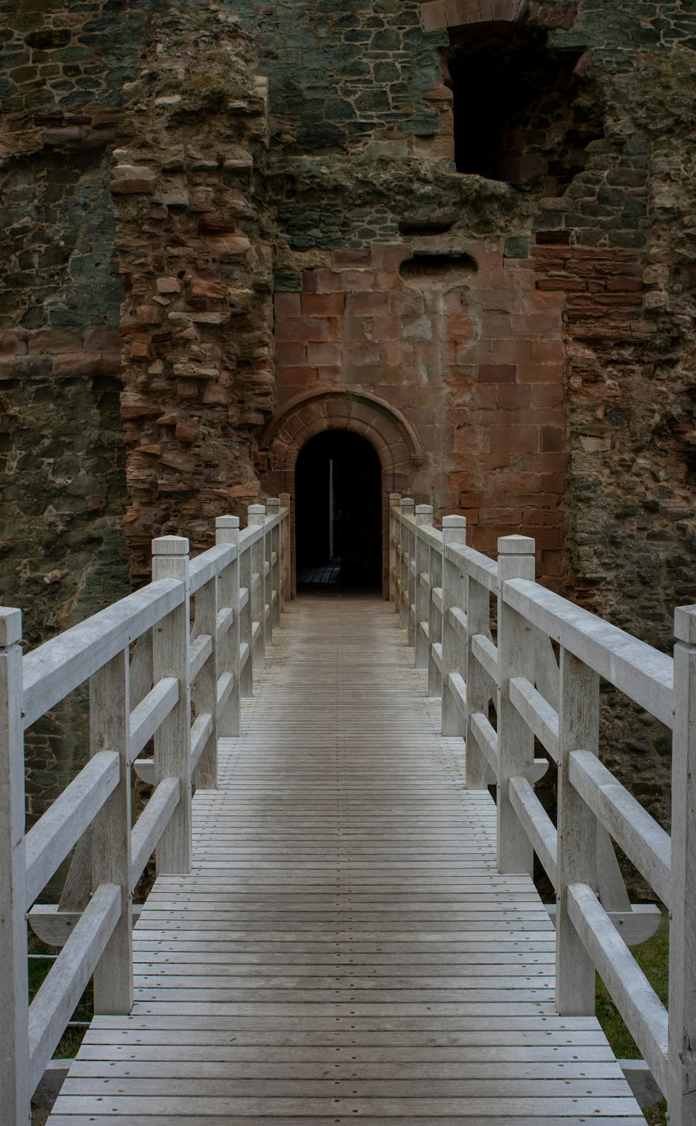 a white wooden bridge leading to a tunnel