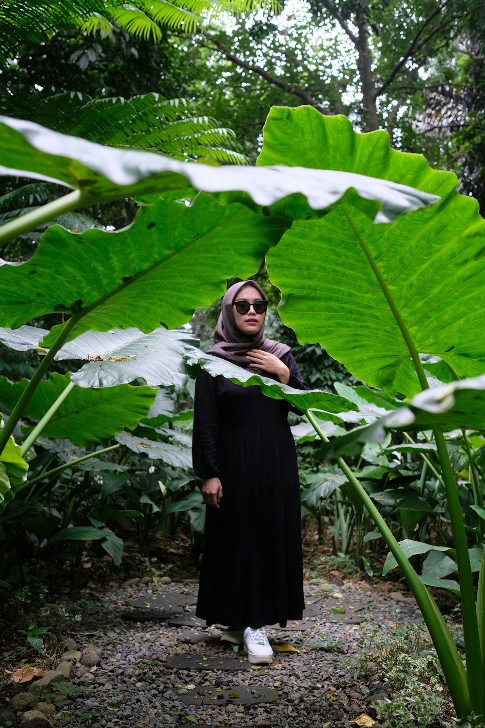 una donna in un vestito nero in piedi in una foresta