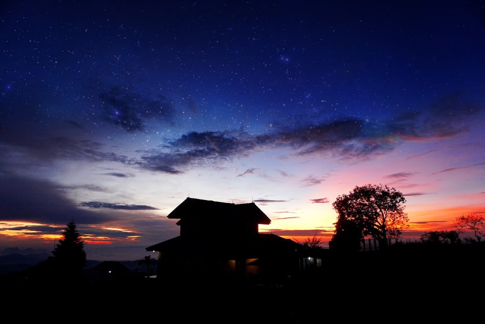 a house is silhouetted against the night sky