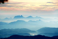 A panoramic view of Ebonyr’s mist-shrouded mountain ranges, captured at twilight with a subtle glow on the peaks.