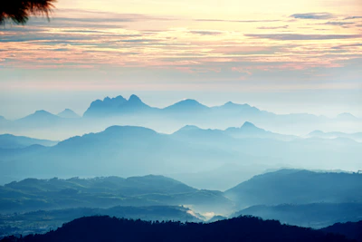 Panoramic view of a misty mountain ridge bathed in soft natural blue light at dawn.