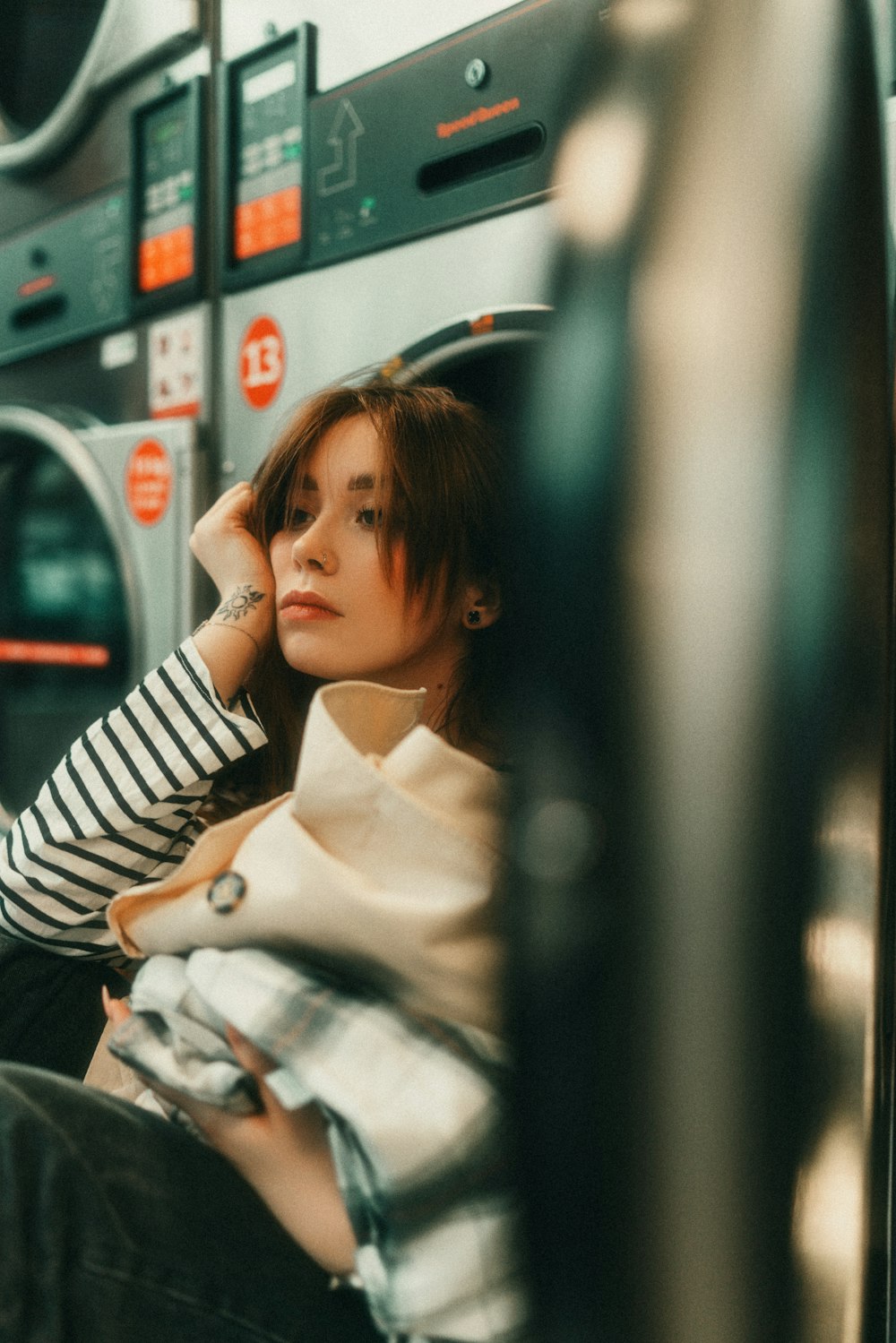 a woman sitting on a train next to a washer