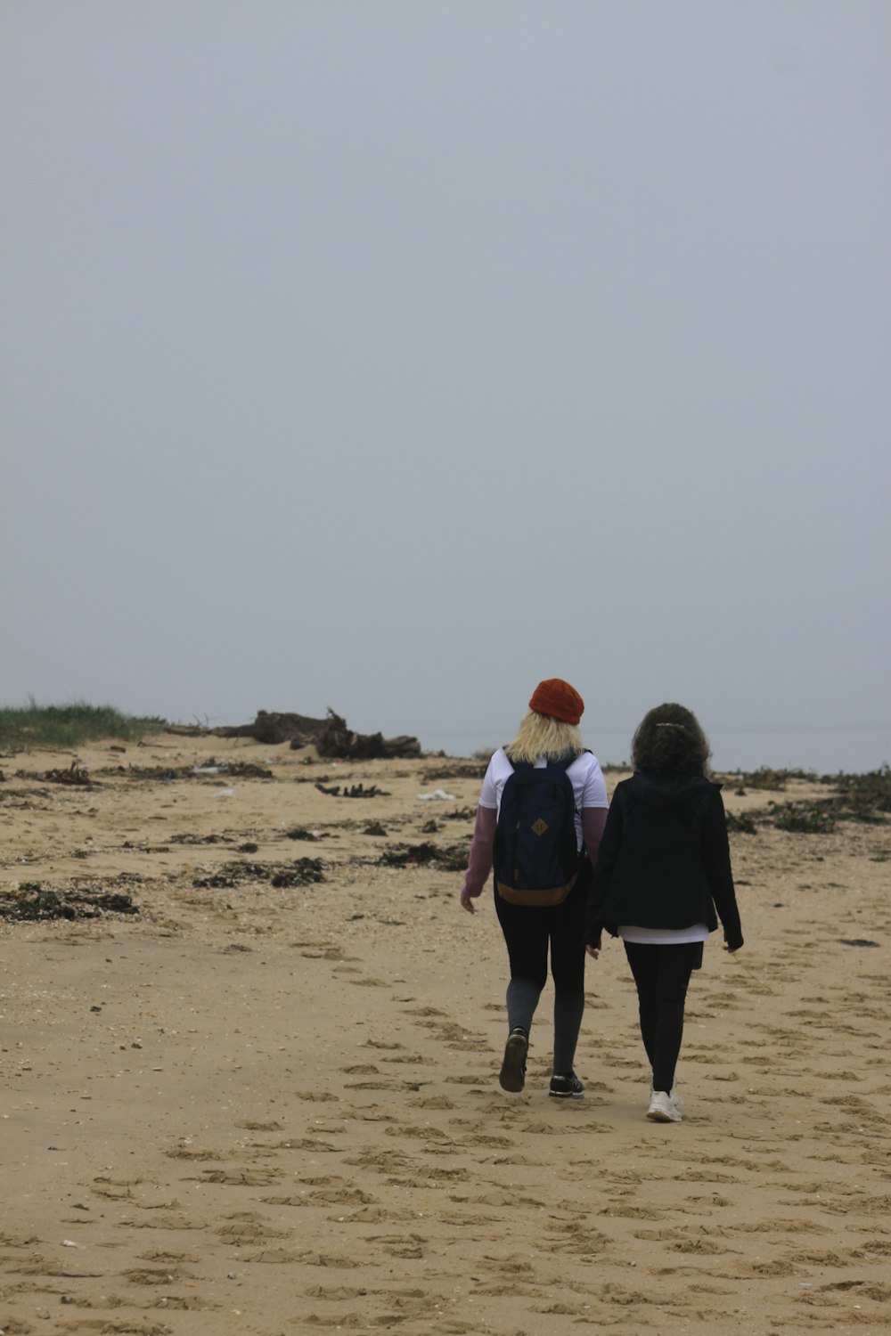 a couple of people walking across a sandy beach