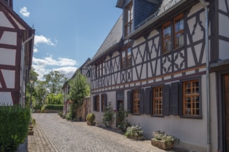 A cozy Bavarian village street with craftsmen working on wooden houses under a clear sky.