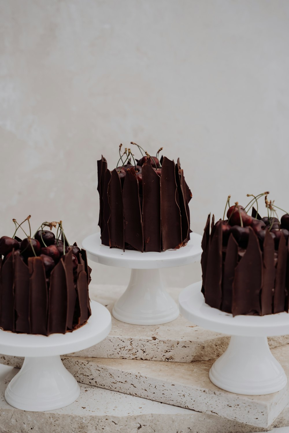 a group of three cakes sitting on top of white pedestals