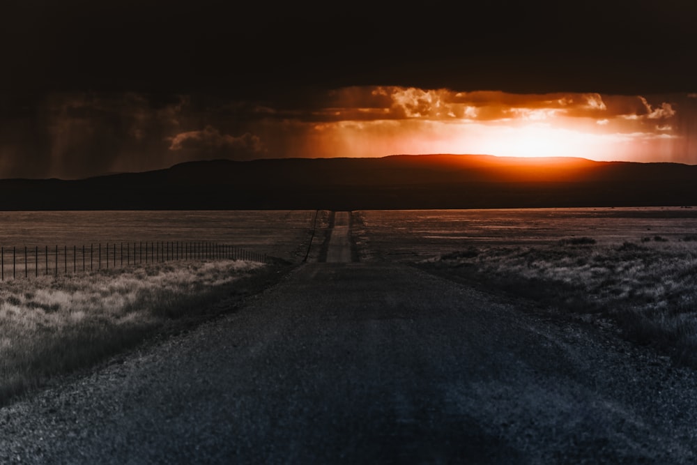 Le soleil se couche sur une route au milieu de nulle part