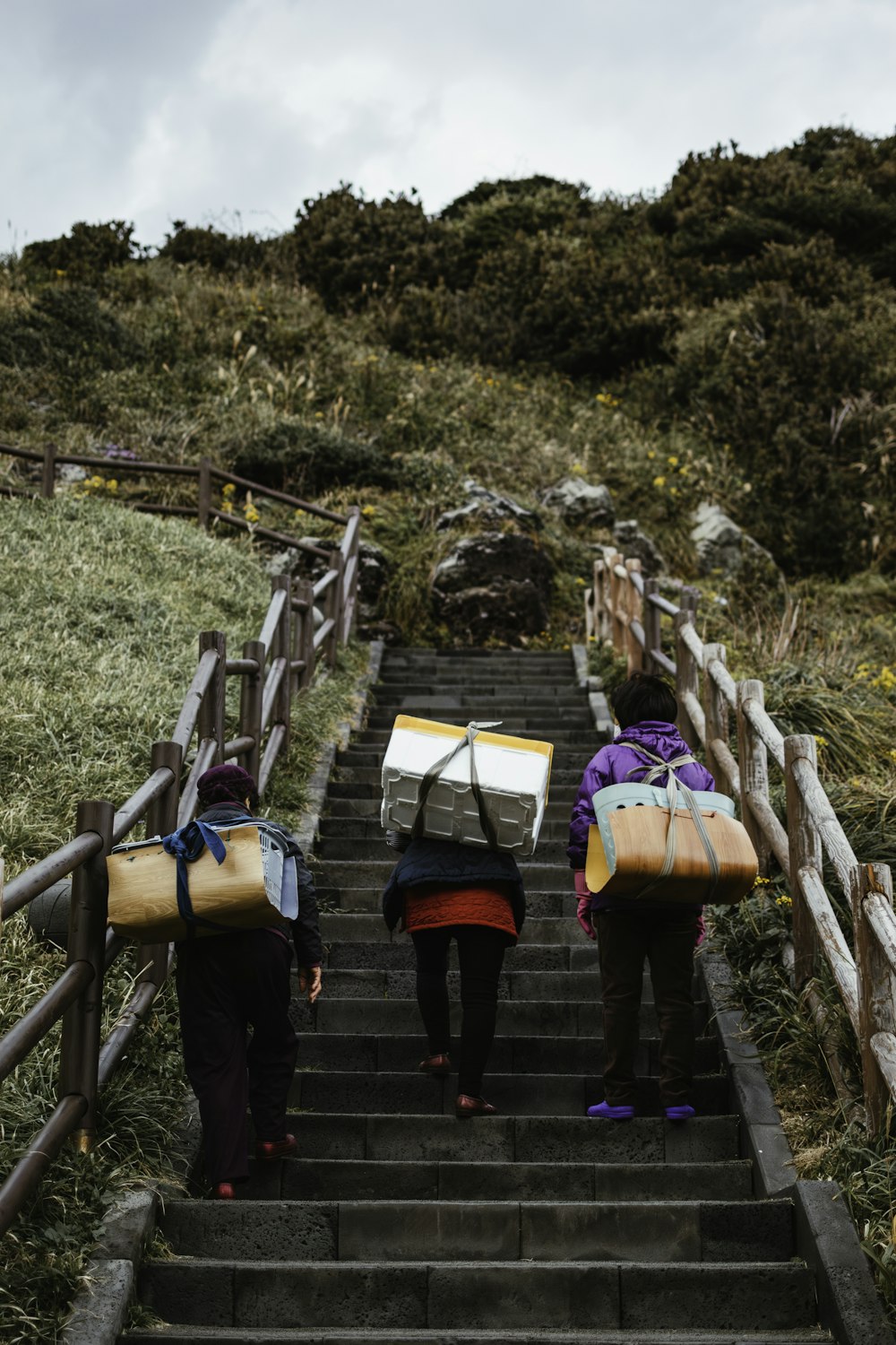 two people walking up a set of stairs carrying luggage