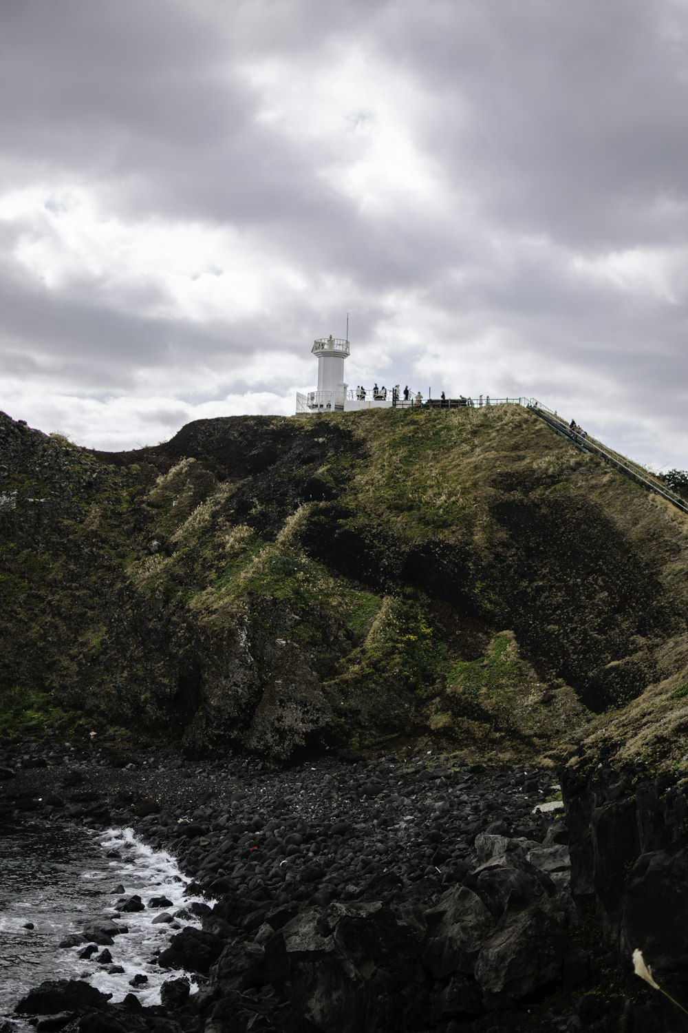 a group of people standing on top of a hill next to the ocean