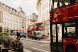 A bustling London street with red buses and people using smartphones.