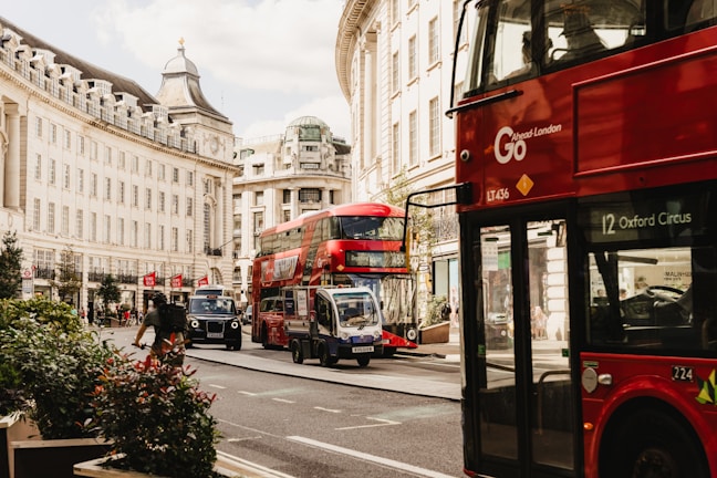 A bustling London street with red buses and people using smartphones.