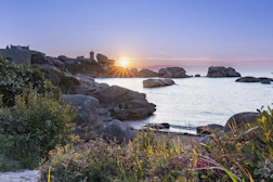 the sun is setting over a rocky beach