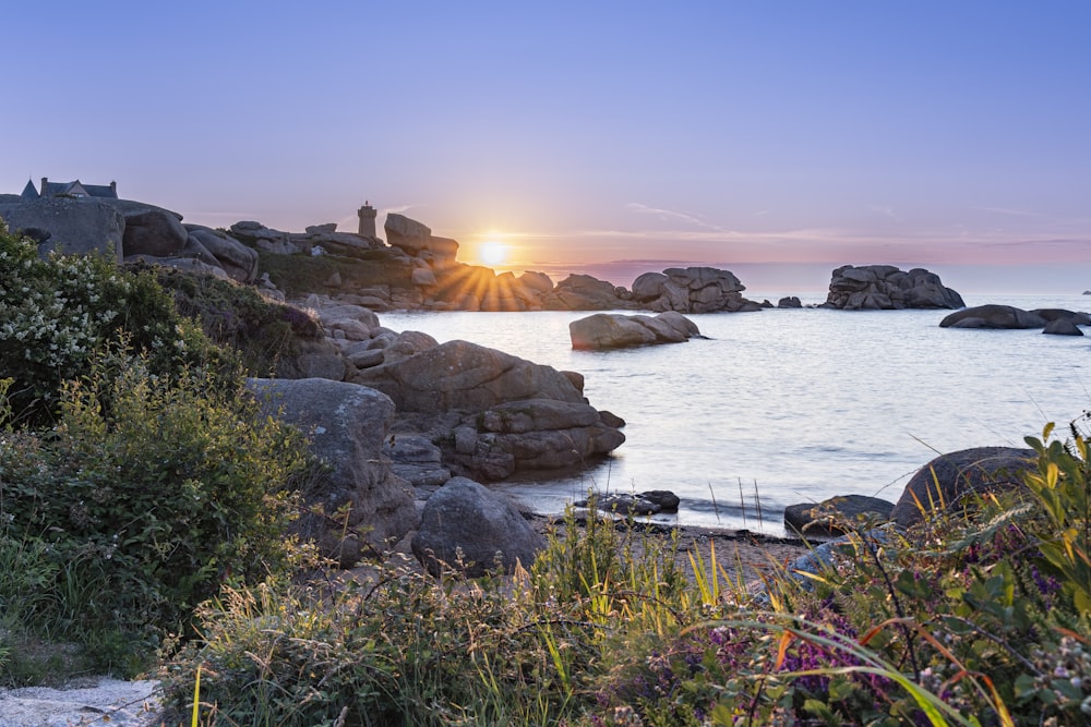 the sun is setting over a rocky beach