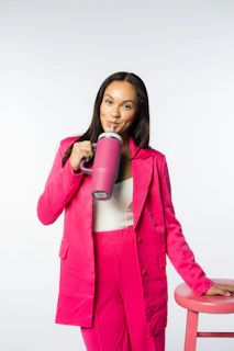 a woman in a pink suit holding a pink coffee cup