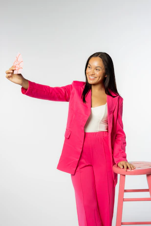 Confident Black woman entrepreneur smiling while holding a sleek NFC tap card in a warm terracotta-toned office.