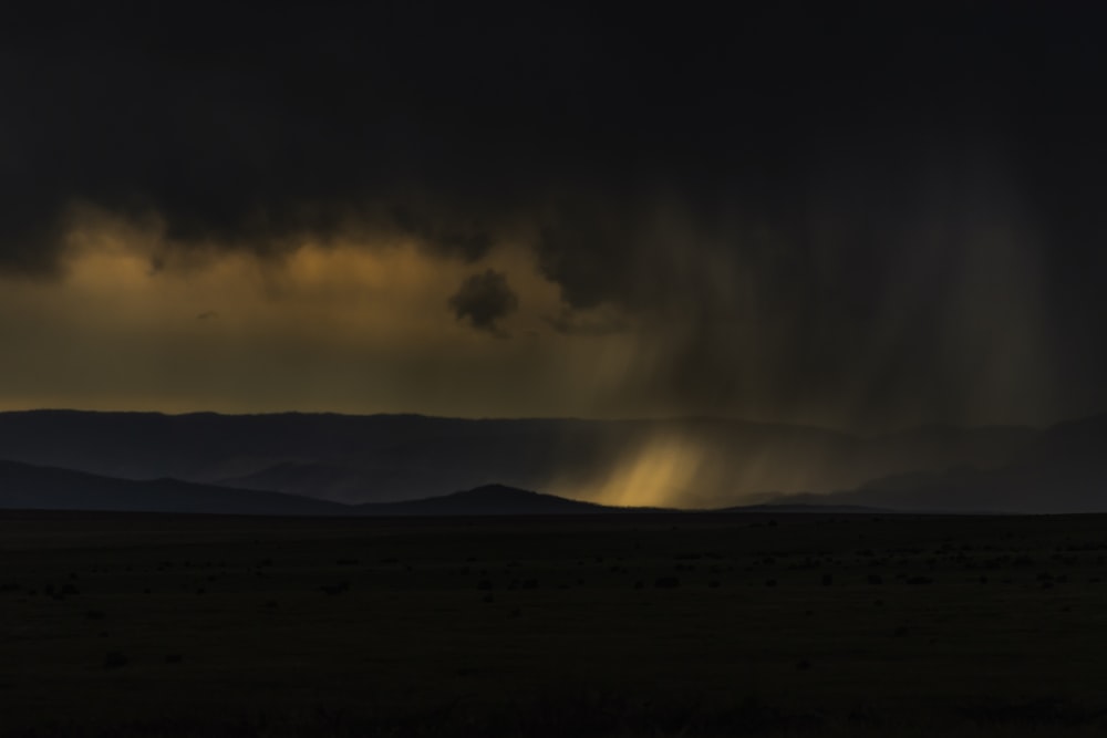 a storm moving across the sky with mountains in the background