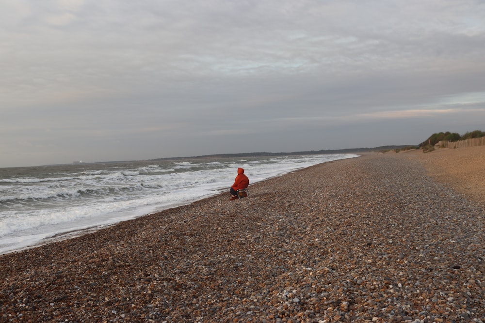 a person sitting on a beach near the ocean
