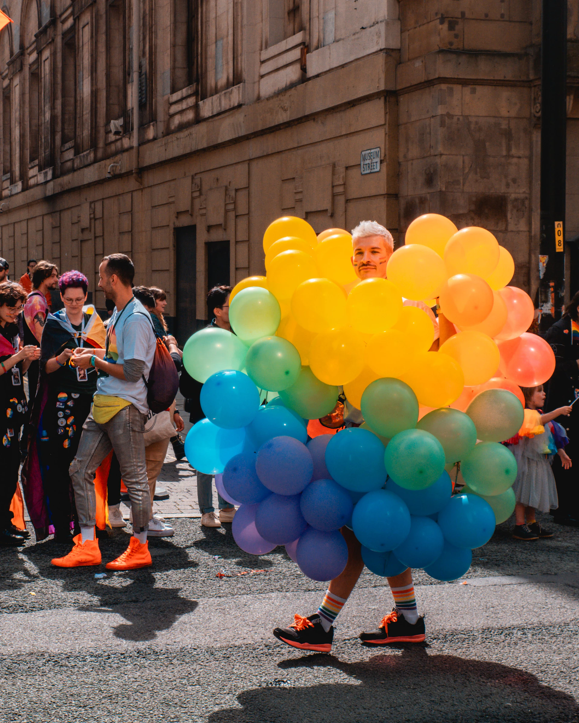 A joyful clown in a bright red and blue costume entertaining children with colorful balloons at a sunny outdoor party.
