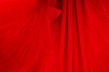 A close-up of rich red fabric texture, highlighting the quality and warmth of the material.