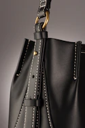 A close-up shot of a finely crafted leather handbag resting on soft beige linen.