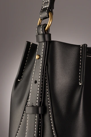A sleek crossbody bag in muted gold, photographed with gentle natural light highlighting its fine texture.