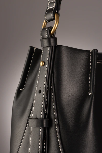 Close-up of a finely stitched black leather handbag with subtle gold accents.