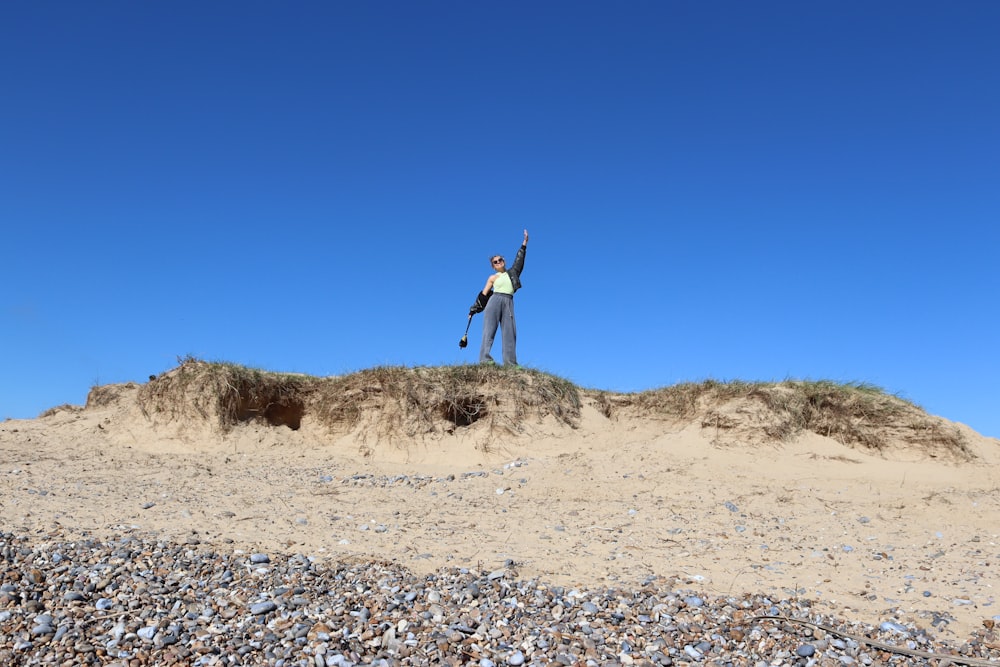 a man standing on top of a sandy hill