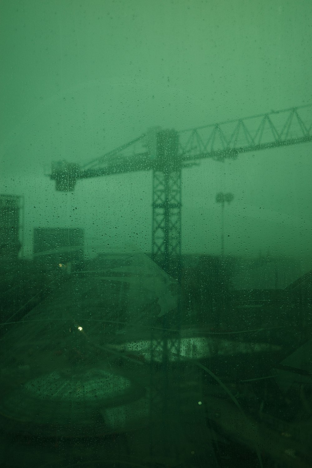 a view of a construction site through a rain soaked window