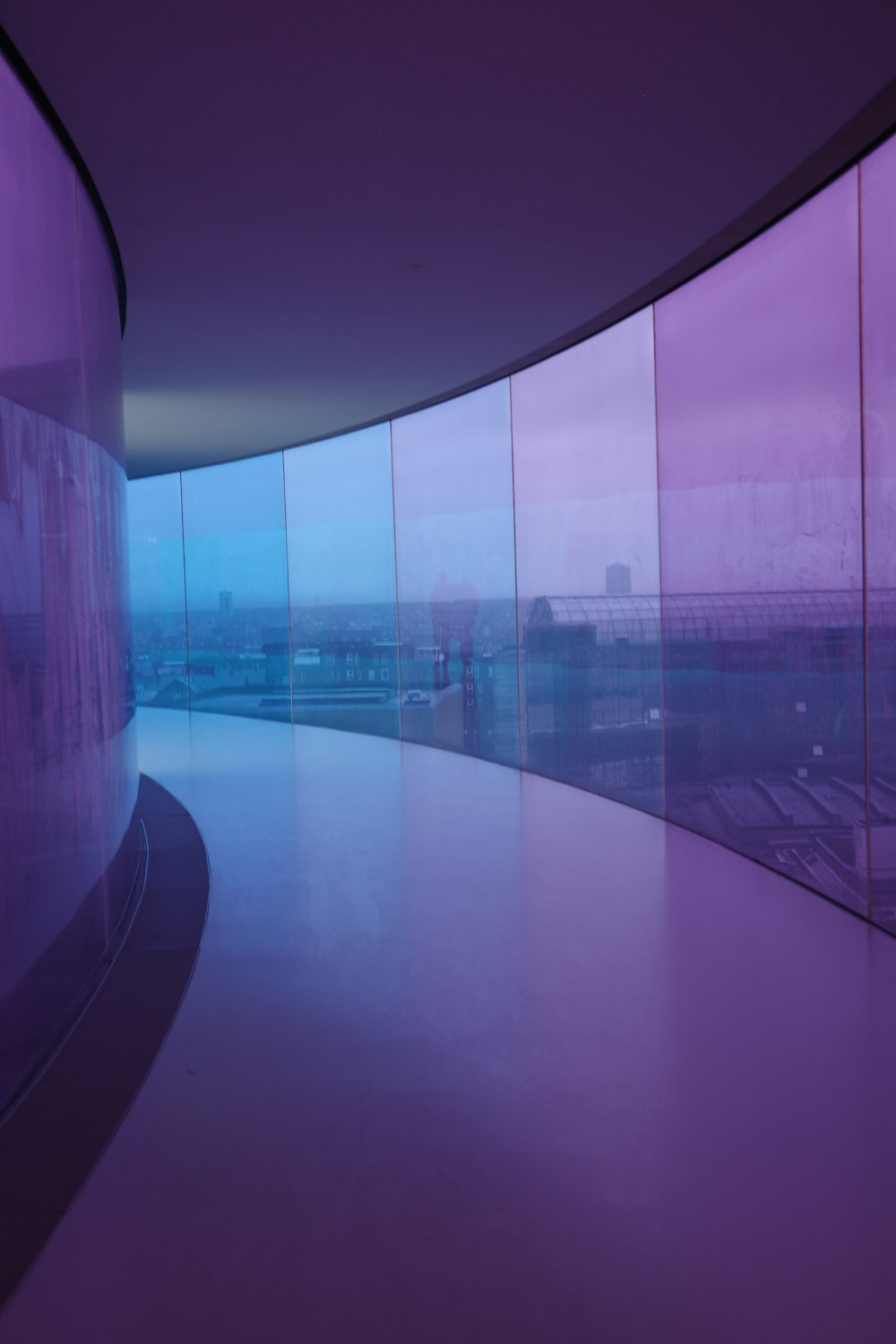 a curved walkway in front of a glass wall