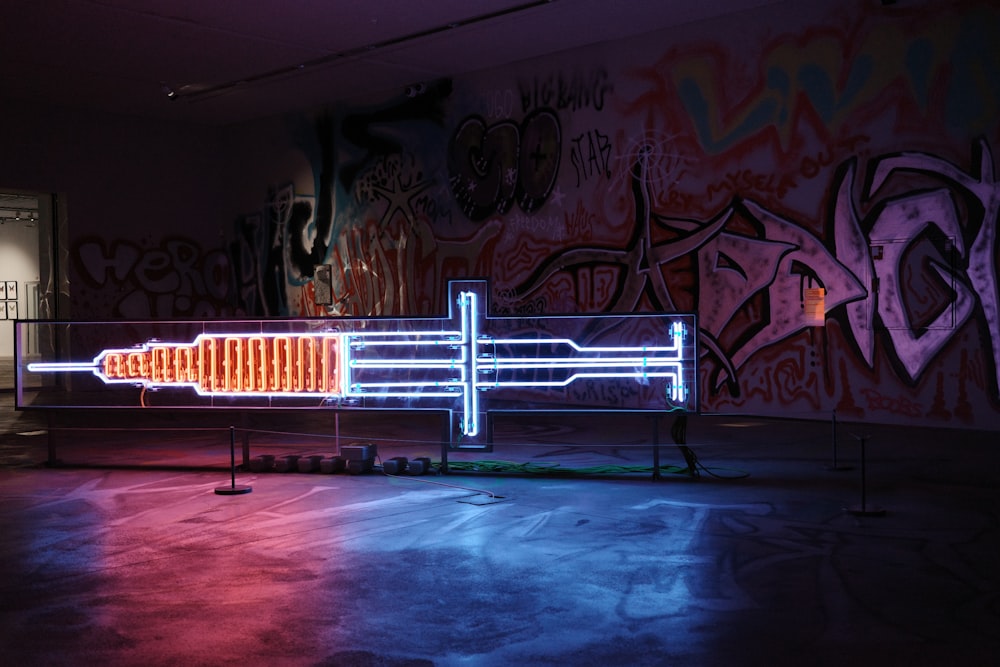 a neon display in a dark room with graffiti on the walls