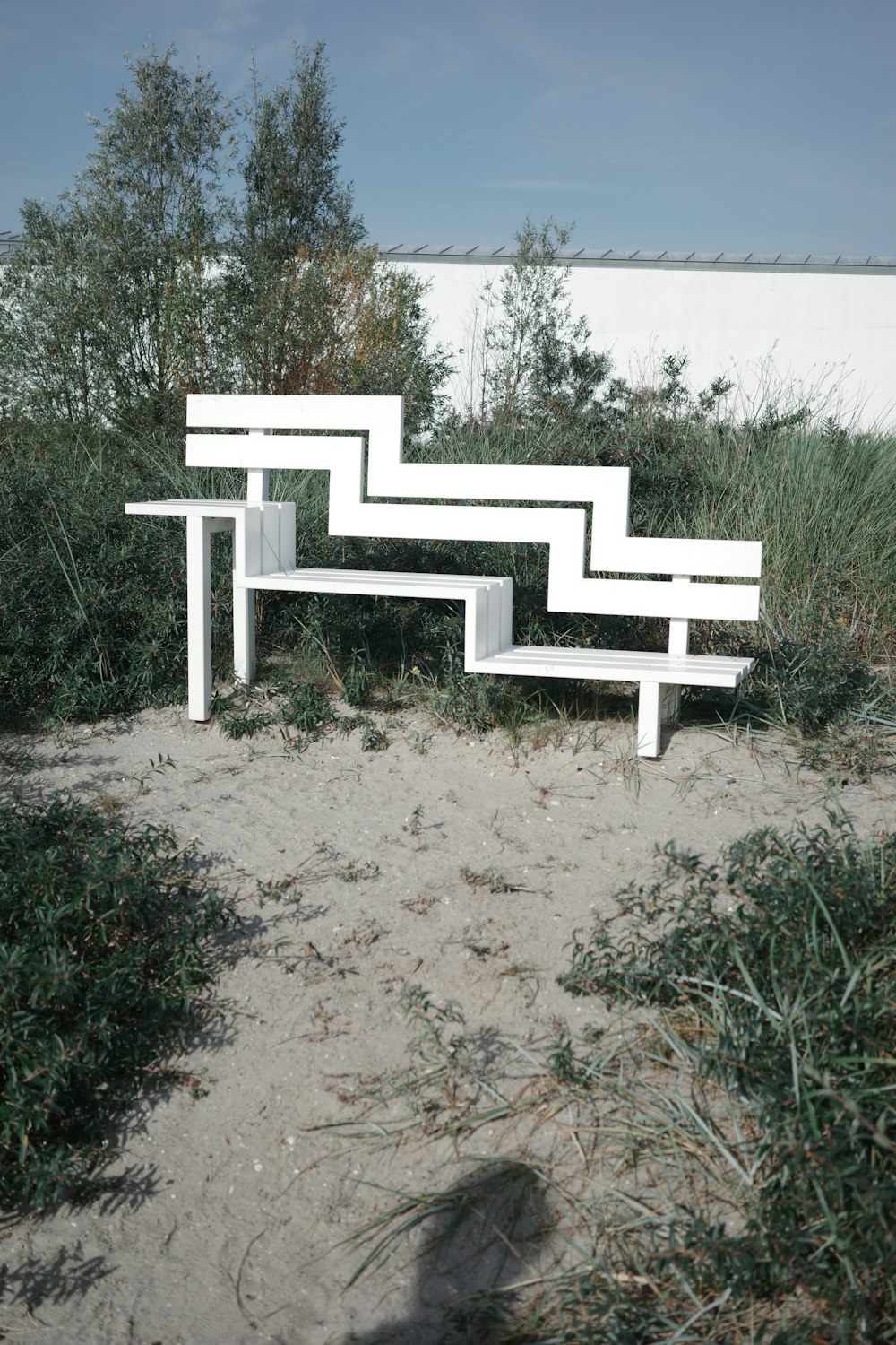 a white bench sitting on top of a sandy beach