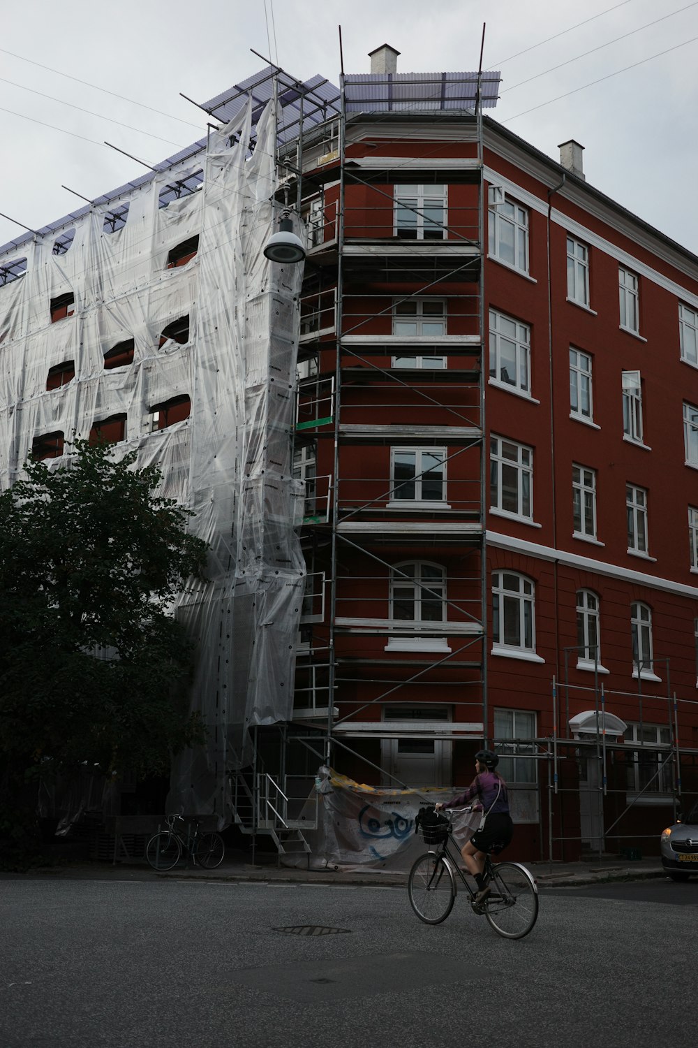 a man riding a bike past a tall red building