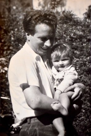 A smiling parent holding a baby using a practical feeding bottle outdoors.