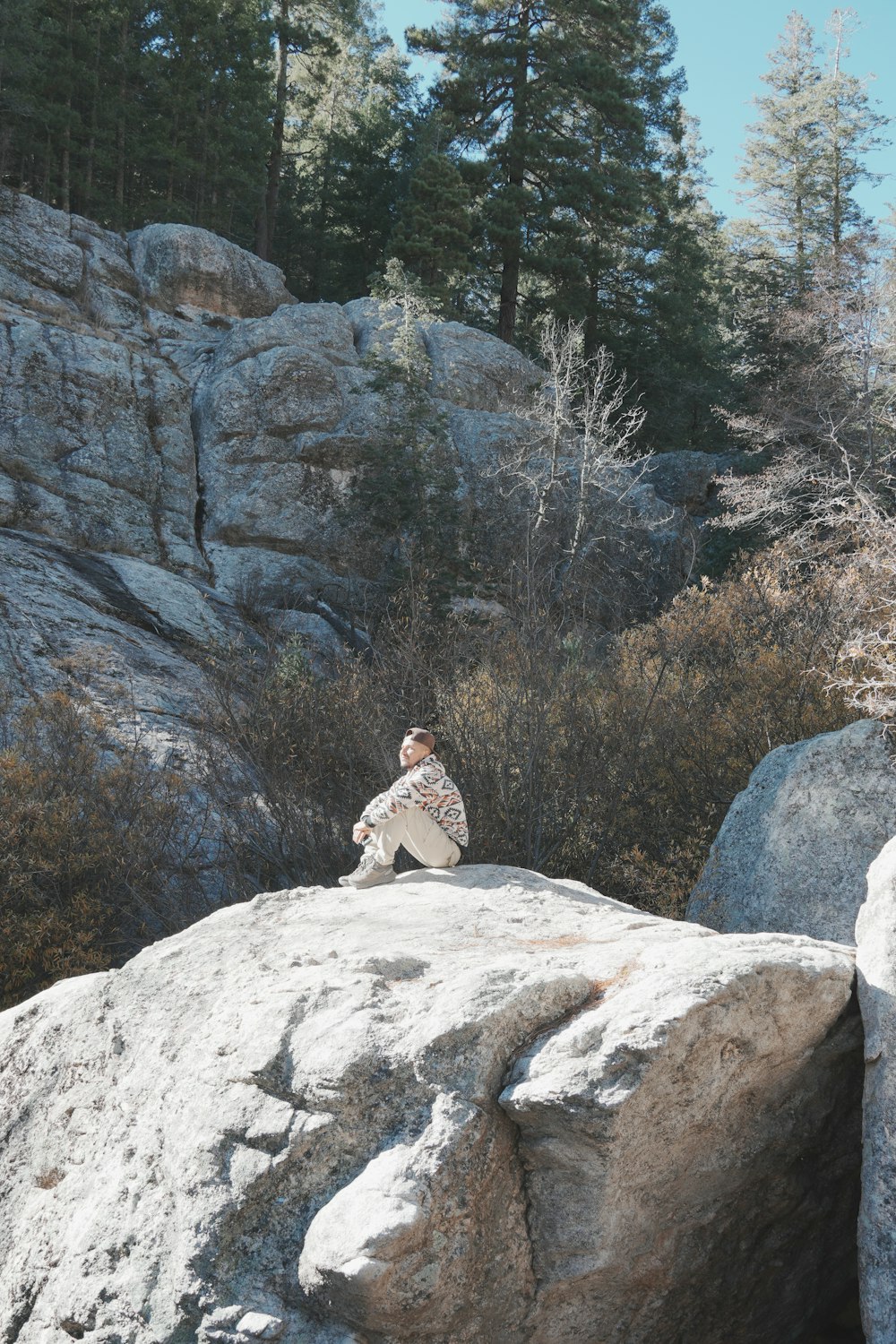 a person sitting on top of a large rock