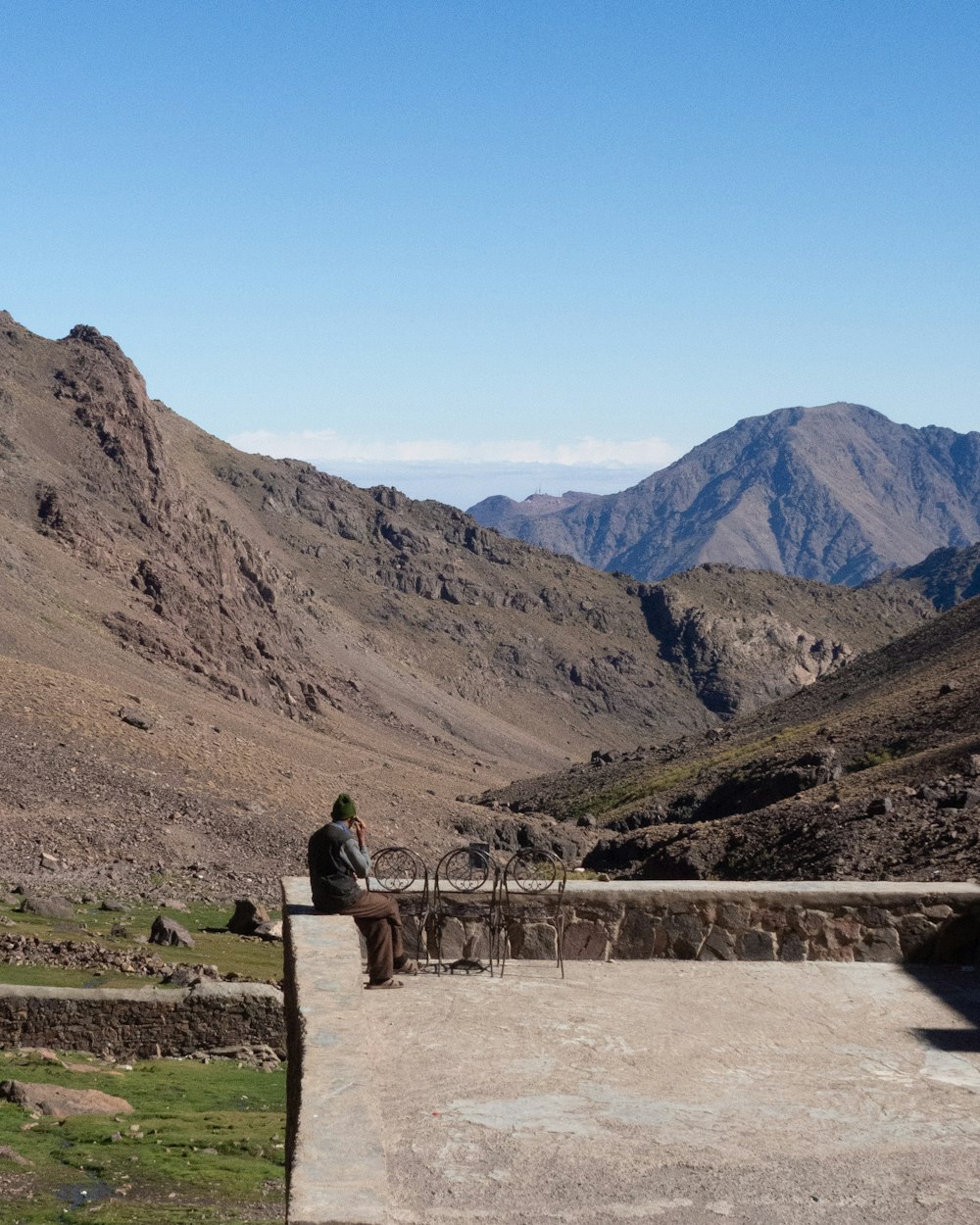 a person sitting on a ledge in the mountains