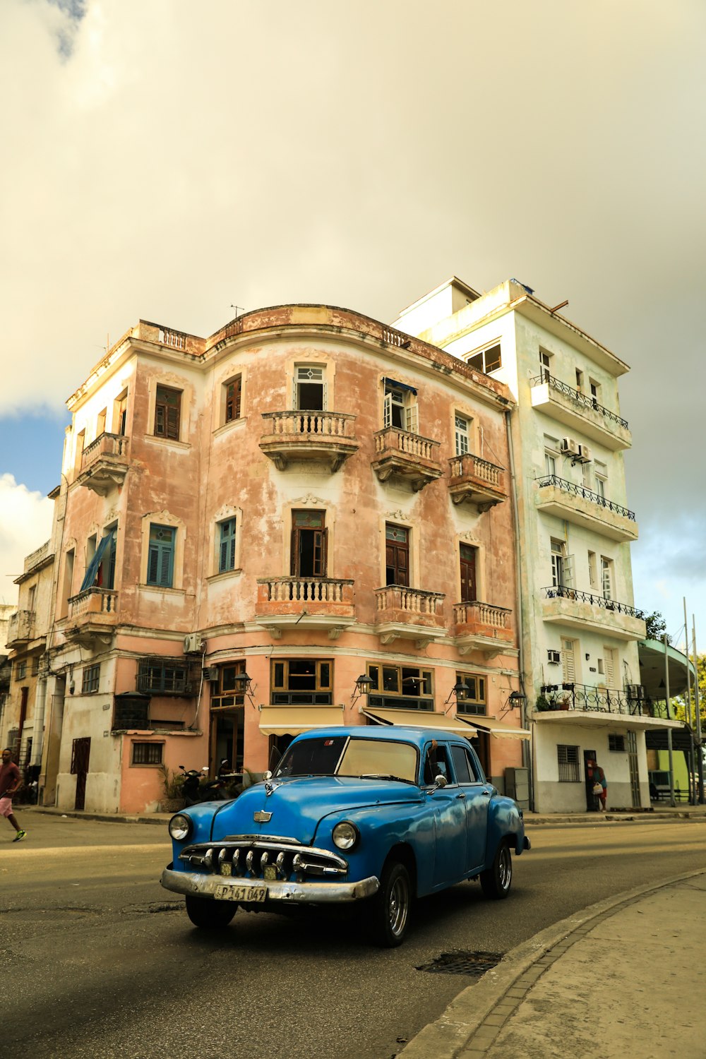 an old blue car parked in front of a building