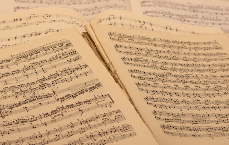An assortment of free downloadable music sheets and sample packs spread out on a wooden desk.