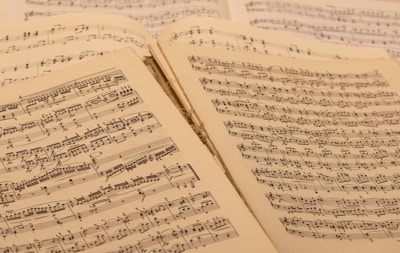 A collection of open sheet music, with musical notations and scores visible on aged paper. The sheets are slightly overlapping, suggesting a well-used and possibly vintage collection.
