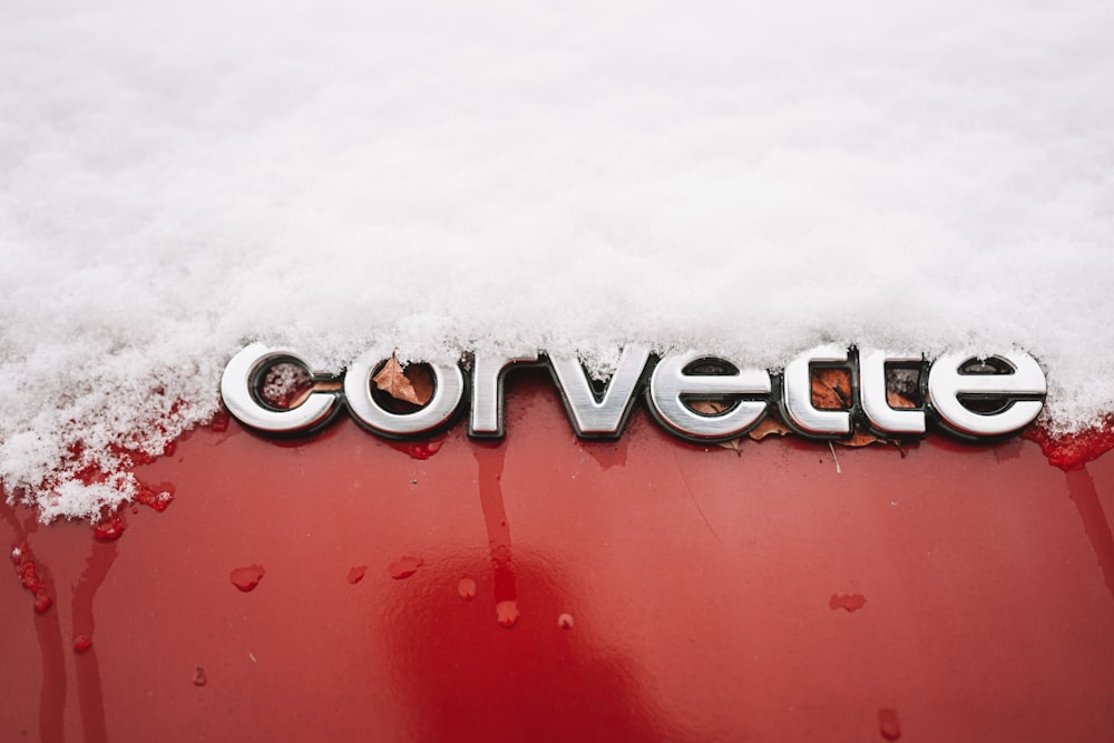 a red car covered in snow with the word corvette written on it